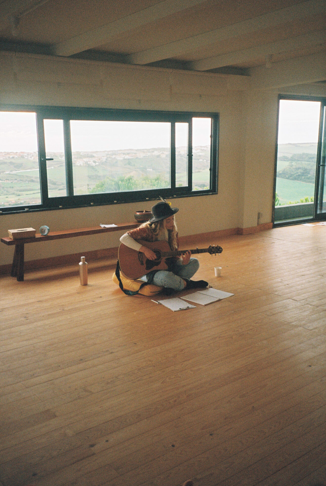 A singer is sitting on the ground and singing the songs while she is playing on the guitare.