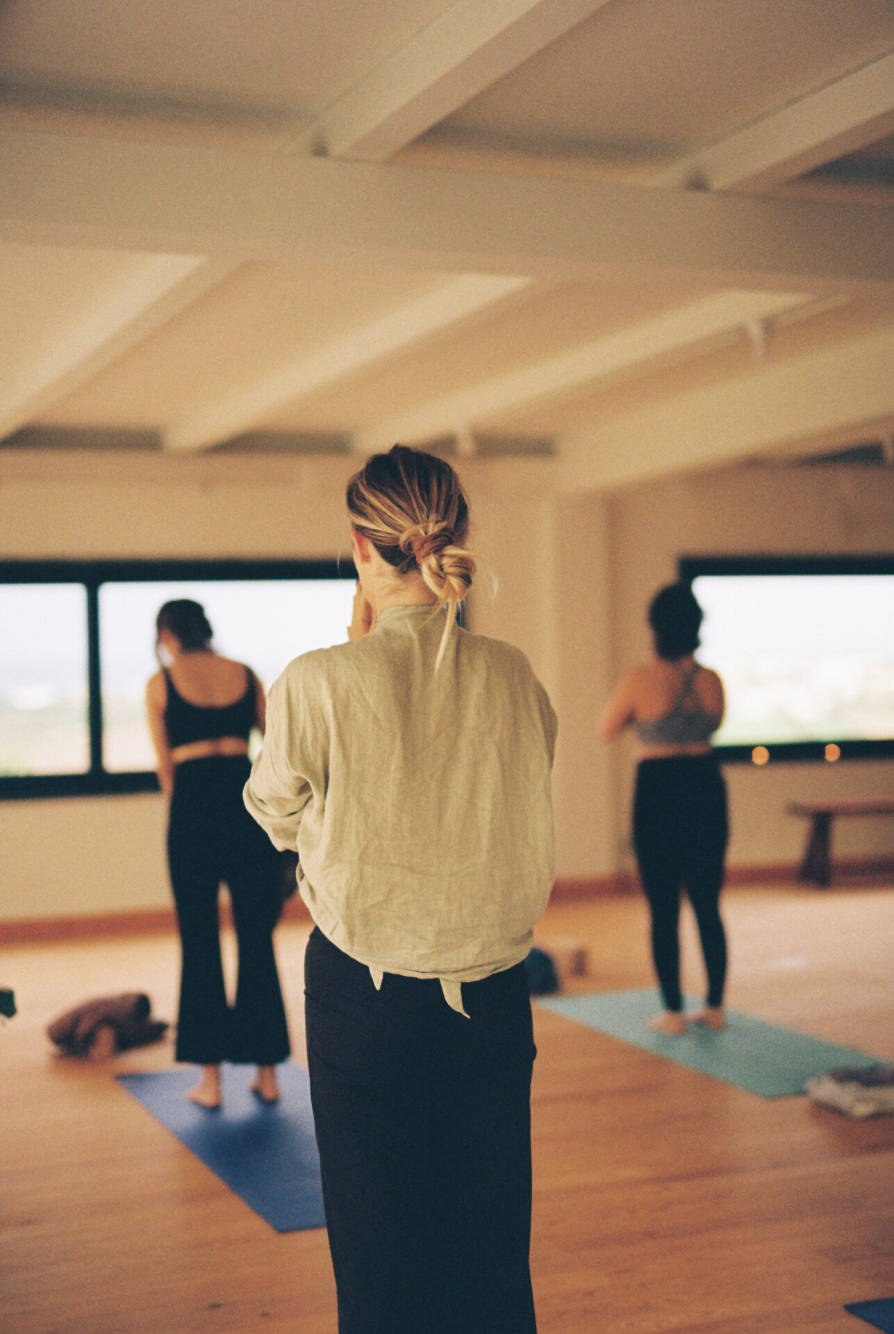 The girl in a linen shirt and cozy black pants is focused on yoga practice. Photo credits: Maximilian Salzer, Wurzelwerkstatt Retreat 2022 Ericeira
